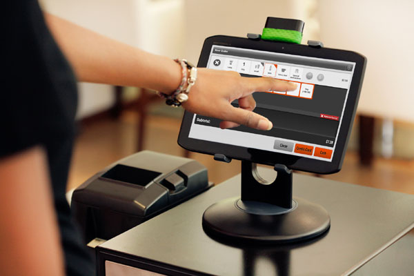 Person using a touchscreen point-of-sale system with a credit card machine beside it.