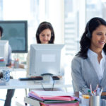 Customer service representatives working at computers in a bright office.