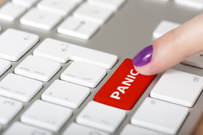 Finger pressing a red "PANIC" key on a computer keyboard.